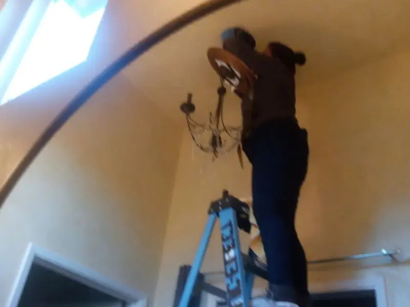 Electrician installing a chandelier in a Round Lake Park residence